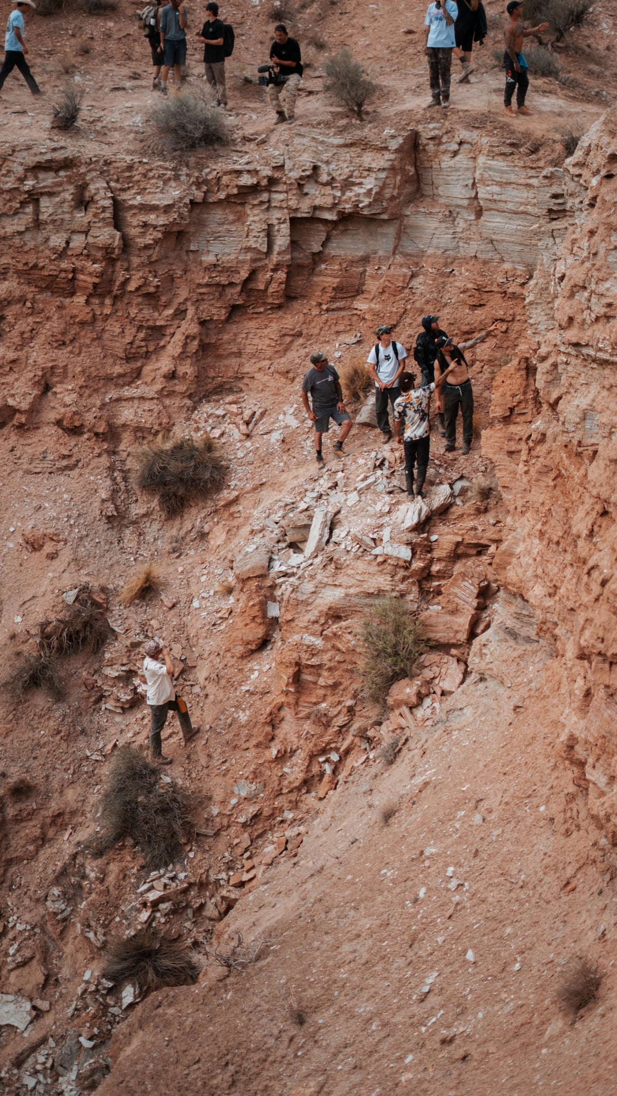 Riders and crews climb a steep slope on scout day.